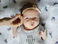 Uroczy 3 tygodniowy noworodek w body z napisem "HUG EVERY DAY", z delikatną opaską na głowie.