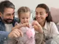 Rodzina uczy córkę oszczędzania. Wkładają monety do świnki-skarbonki, planując przyszłość, gdzie każdy grosz się liczy, nawet 12000 na dziecko.