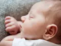 Śpiące niemowlę na brzuchu, z zamkniętymi oczami i delikatną główką. Czy niemowlę może spać na brzuchu? Bezpieczny sen to podstawa.