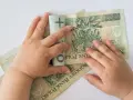 Dziecko bawi się banknotami 100 zł. Czy to już 12 tys na dziecko?