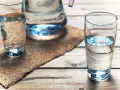 Dwa szklanki z wodą i dzbanek na drewnianym stole. Zastanawiasz się, jaka woda dla niemowlaka? Czysta i świeża, jak ta na zdjęciu.