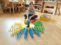 Chłopiec bawi się w przedszkolu Montessori, układając kolorowe krzesełka wokół globusa. To pokazuje, montessori co to za metoda nauczania.