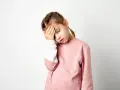 Zmęczona dziewczynka z ręką na czole, być może objawy anemii u niemowlaka, choć to starsze dziecko.
