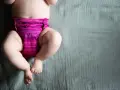 Urocze nóżki dziecka w różowej pieluszce. Czas zacząć naukę jak odpieluchować dziecko.