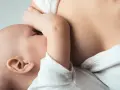 Dziecko karmione piersią, czuły moment bliskości. Nawał pokarmu to naturalny etap rozwoju malucha.