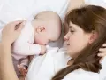 Mama tuli tulista, kpi karmienie. Dziecko przytulone do piersi, spokojne i bezpieczne.