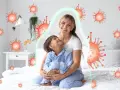 Mama tuli dziecko, które ma kaszel w nocy. Wokół nich unoszą się wirusy, ale chroni je zielona bariera.