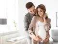 Mężczyzna obejmuje brzuch kobiety, okazując troskę i wsparcie. To piękny obraz opieki nad żoną po porodzie, pełen miłości i oczekiwania.