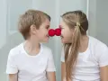 Uśmiechnięte rodzeństwo z czerwonymi nosami klauna na nosach.