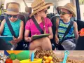 Dzieci w samochodzie, jedno z nich to iPad kid, podróżują na wakacje. Słońce, plaża i zabawki zapowiadają świetny czas.