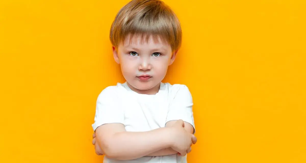 Mały chłopiec z założonymi rękami, wyrażający bunt 4 latka. Jego mina mówi wszystko.