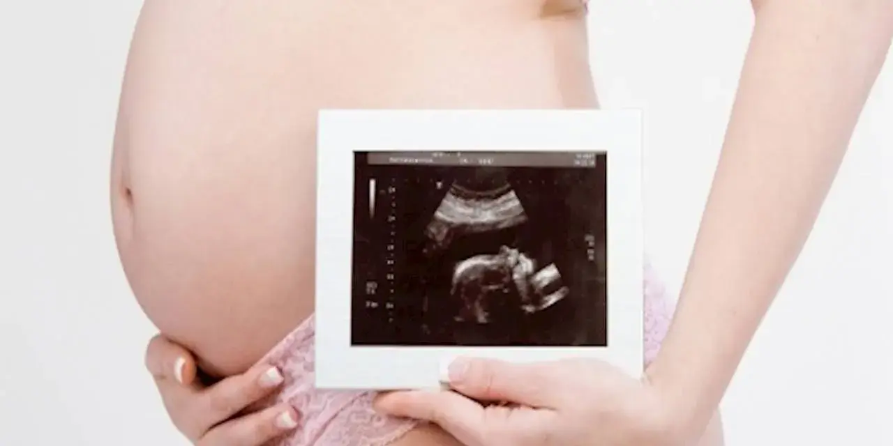 Ciężarna kobieta trzyma zdjęcie USG. To badanie, które pokazuje, co oznacza rozwój dziecka.