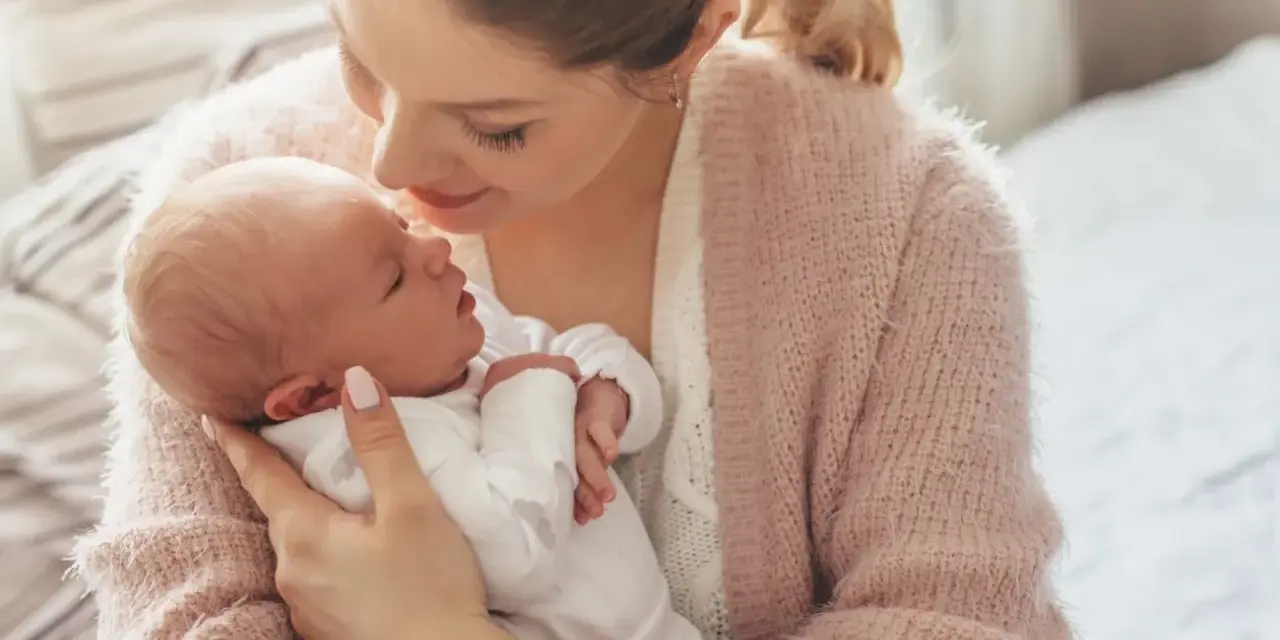 Delikatna pozycja do odbijania noworodka w ramionach mamy, która tuli go z miłością.