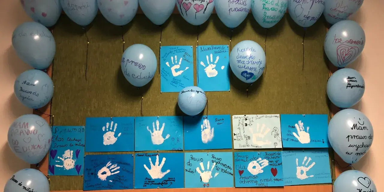 Dzień dziecka w szkole: niebieskie balony z napisami o prawach dzieci i rysunki dłoni.