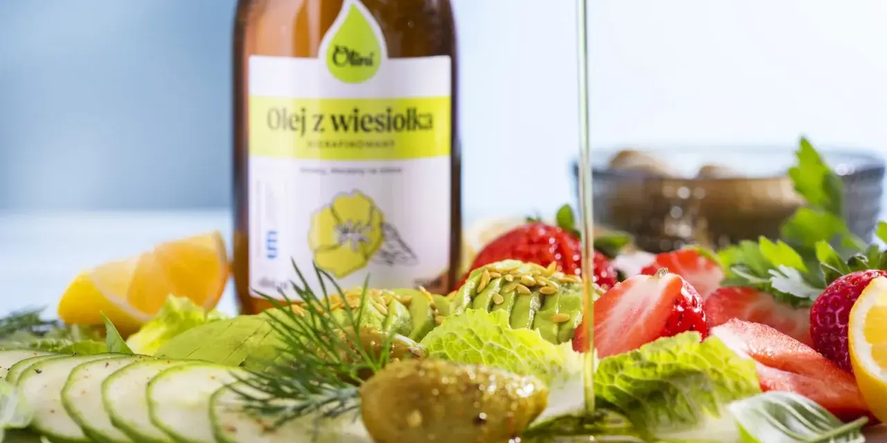 Butelka oleju z wiesiołka i sałatka z awokado, truskawek, ogórka i cytryny.