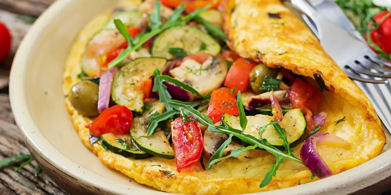 Puszysty omlet dla niemowlaka z cukinią, pomidorkami, oliwkami i rukolą. Zdrowy i kolorowy posiłek.