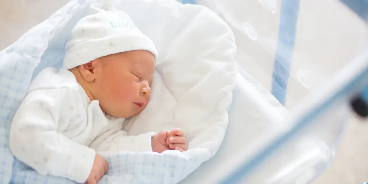 Śpiący noworodek w czepku z napisem "DADDY". To idealny moment na becikowe dla kogoś tak małego.