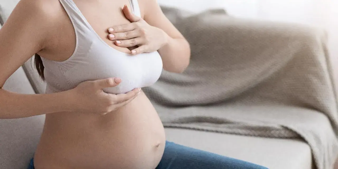 Kobieta w ciąży, dotykająca swoich piersi. Zmiany w sutkach w ciąży to naturalny proces.