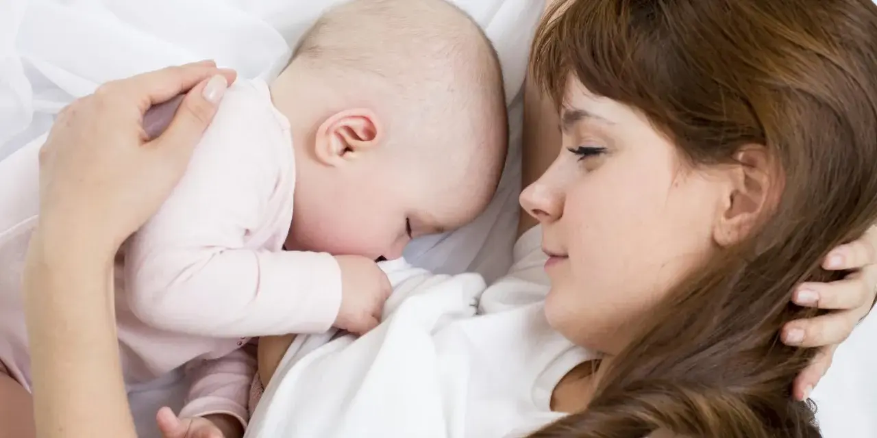 Mama tuli tulista, kpi karmienie. Dziecko przytulone do piersi, spokojne i bezpieczne.