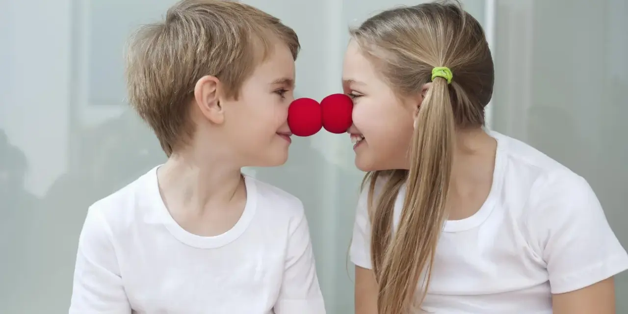 Uśmiechnięte rodzeństwo z czerwonymi nosami klauna na nosach.