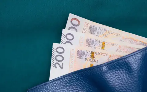 Trzy banknoty po 200 zł w granatowym portfelu. Zastanawiasz się, ile wynosi zasiłek celowy?