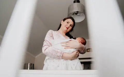 Matka tuli dziecko, które lekko się wierciło, jakby czuło stan podgorączkowy u niemowlaka.
