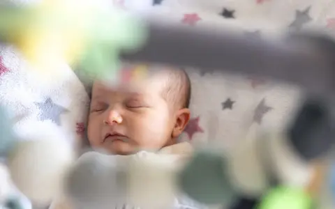 Śpiące dziecko na kocyku w gwiazdki. Może to być moment regresu snu, kiedy maluch potrzebuje więcej spokoju.