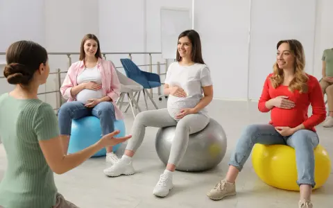 Ciężarne kobiety siedzą na piłkach gimnastycznych podczas zajęć w szkole rodzenia.