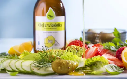 Butelka oleju z wiesiołka i sałatka z awokado, truskawek, ogórka i cytryny.