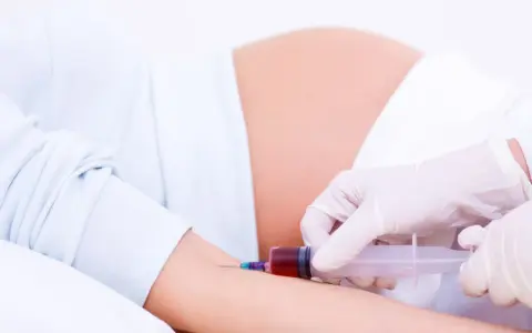 Pobieranie krwi do badań w 15 tygodniu ciąży. Brzuch ciężarnej i ręka z igłą strzykawki.