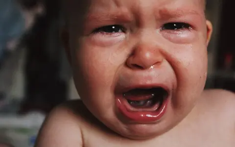 Malutkie dziecko płacze, ma zaczerwienione oczy i mokry nosek. To pewnie katar przy ząbkowaniu, który sprawia mu ból.