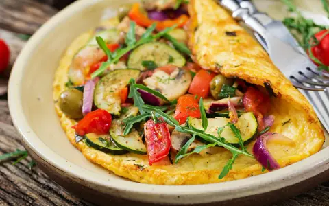 Puszysty omlet dla niemowlaka z cukinią, pomidorkami, oliwkami i rukolą. Zdrowy i kolorowy posiłek.
