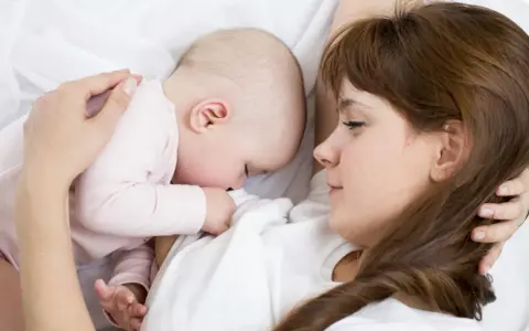 Mama tuli tulista, kpi karmienie. Dziecko przytulone do piersi, spokojne i bezpieczne.