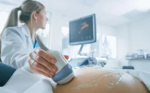 Lekarka wykonuje USG brzucha ciężarnej, monitorując przebieg ciąży. Badanie to jest kluczowe, zwłaszcza gdy stosowana jest heparyna w ciąży.