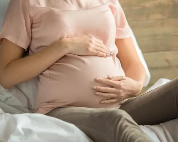 Kobieta w ciąży z dłońmi na brzuchu, martwiąca się o niskie erytrocyty w ciąży.