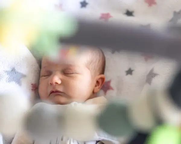 Śpiące dziecko na kocyku w gwiazdki. Może to być moment regresu snu, kiedy maluch potrzebuje więcej spokoju.