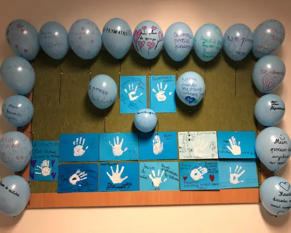 Dzień dziecka w szkole: niebieskie balony z napisami o prawach dzieci i rysunki dłoni.