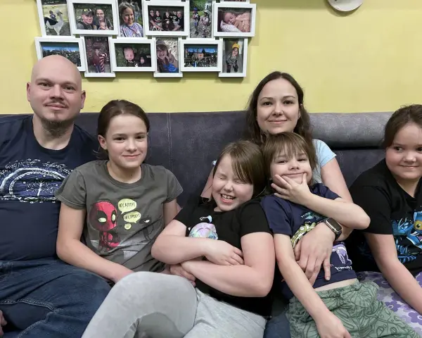 Szczęśliwa rodzina wielodzietna siedzi na kanapie. Rodzice i pięcioro dzieci uśmiechają się do aparatu.
