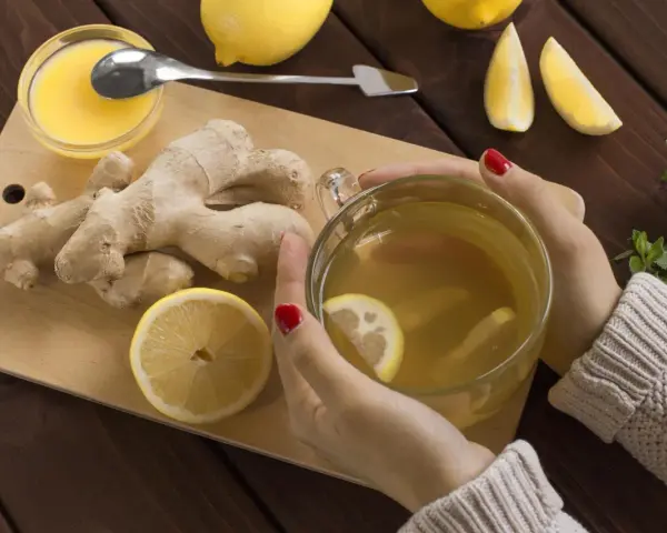 Kobieta pije herbatę z imbirem i cytryną, która pomaga w dolegliwościach w ciąży.