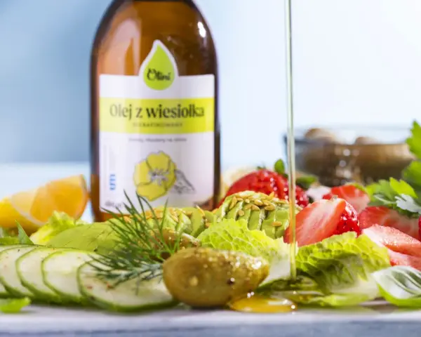 Butelka oleju z wiesiołka i sałatka z awokado, truskawek, ogórka i cytryny.