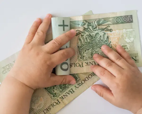 Dziecko bawi się banknotami 100 zł. Czy to już 12 tys na dziecko?