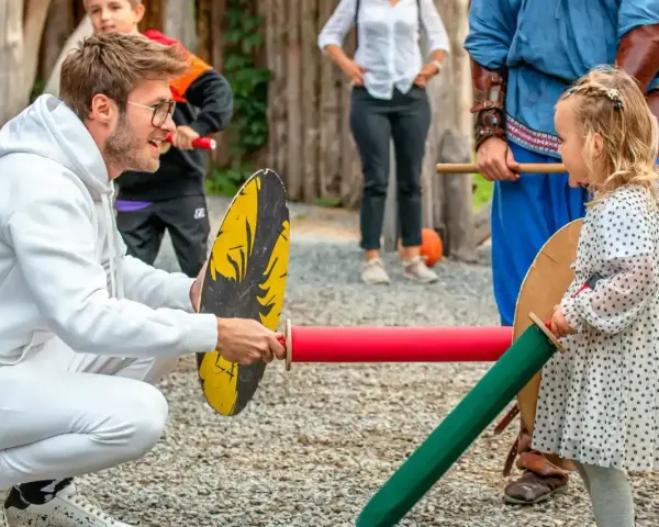 Chłopiec i dziewczynka ćwiczą walkę na miecze. Widać, że dziewczynka ma odwagę i determinację, co są jej mocne strony.