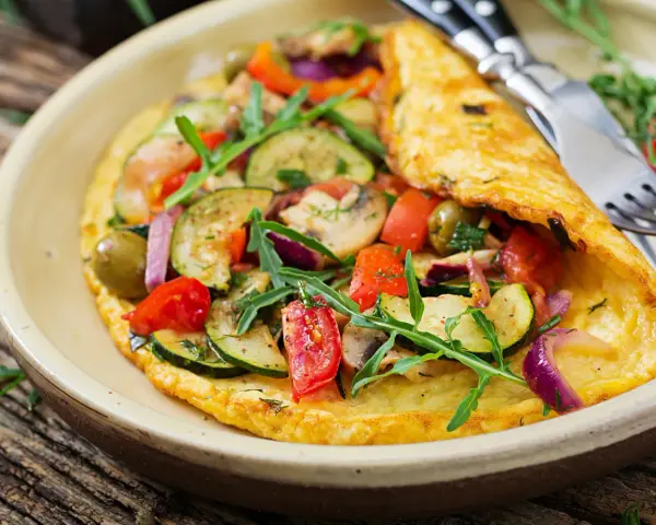 Puszysty omlet dla niemowlaka z cukinią, pomidorkami, oliwkami i rukolą. Zdrowy i kolorowy posiłek.