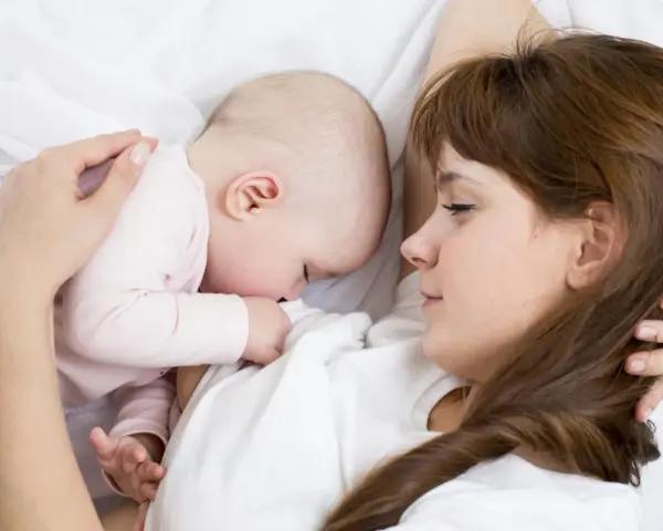 Mama tuli tulista, kpi karmienie. Dziecko przytulone do piersi, spokojne i bezpieczne.