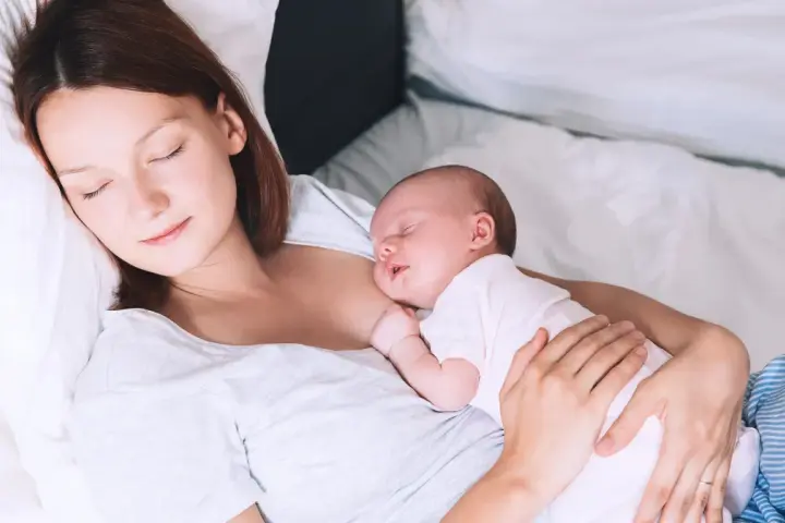 Matka śpi z dzieckiem przy piersi, doświadczając piękna laktacji.