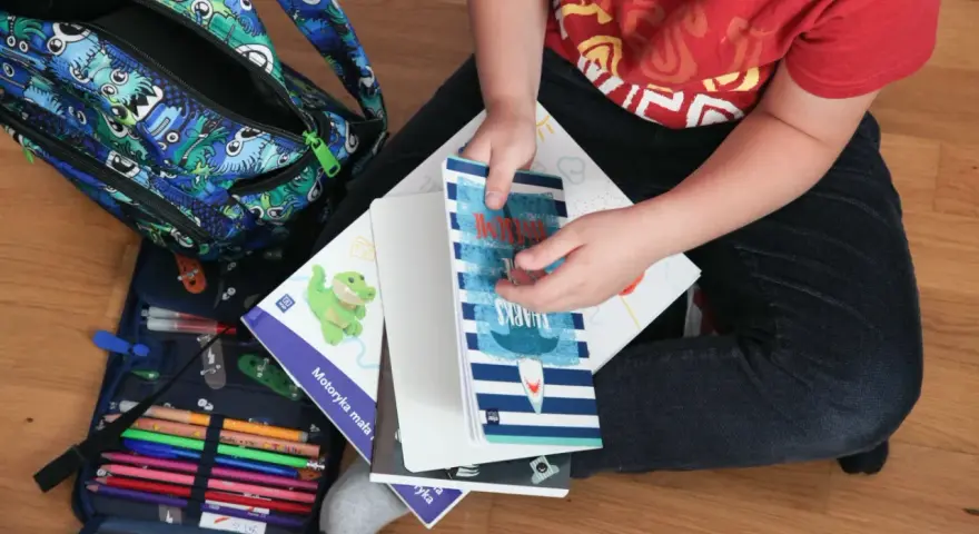 Chłopiec przygotowuje się do szkoły, rozpakowując plecak z potworkami. Wśród książek i zeszytów, w tym z rekinami, czeka go nauka i zabawa. To idealny zestaw na 300 plus dla 6 latka.