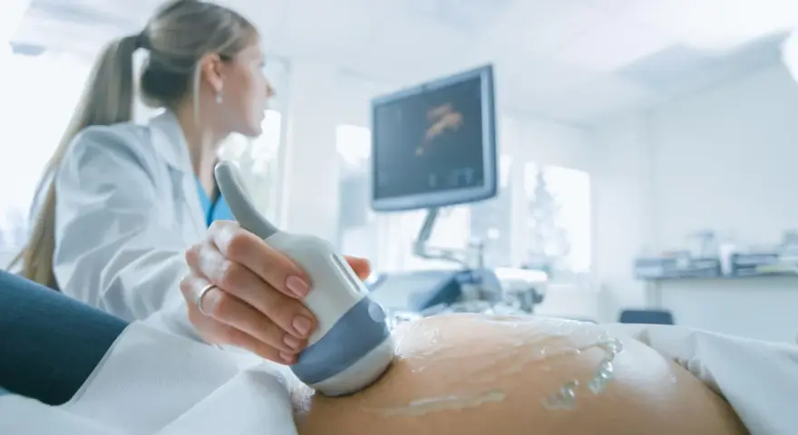 Lekarka wykonuje USG brzucha ciężarnej, monitorując przebieg ciąży. Badanie to jest kluczowe, zwłaszcza gdy stosowana jest heparyna w ciąży.