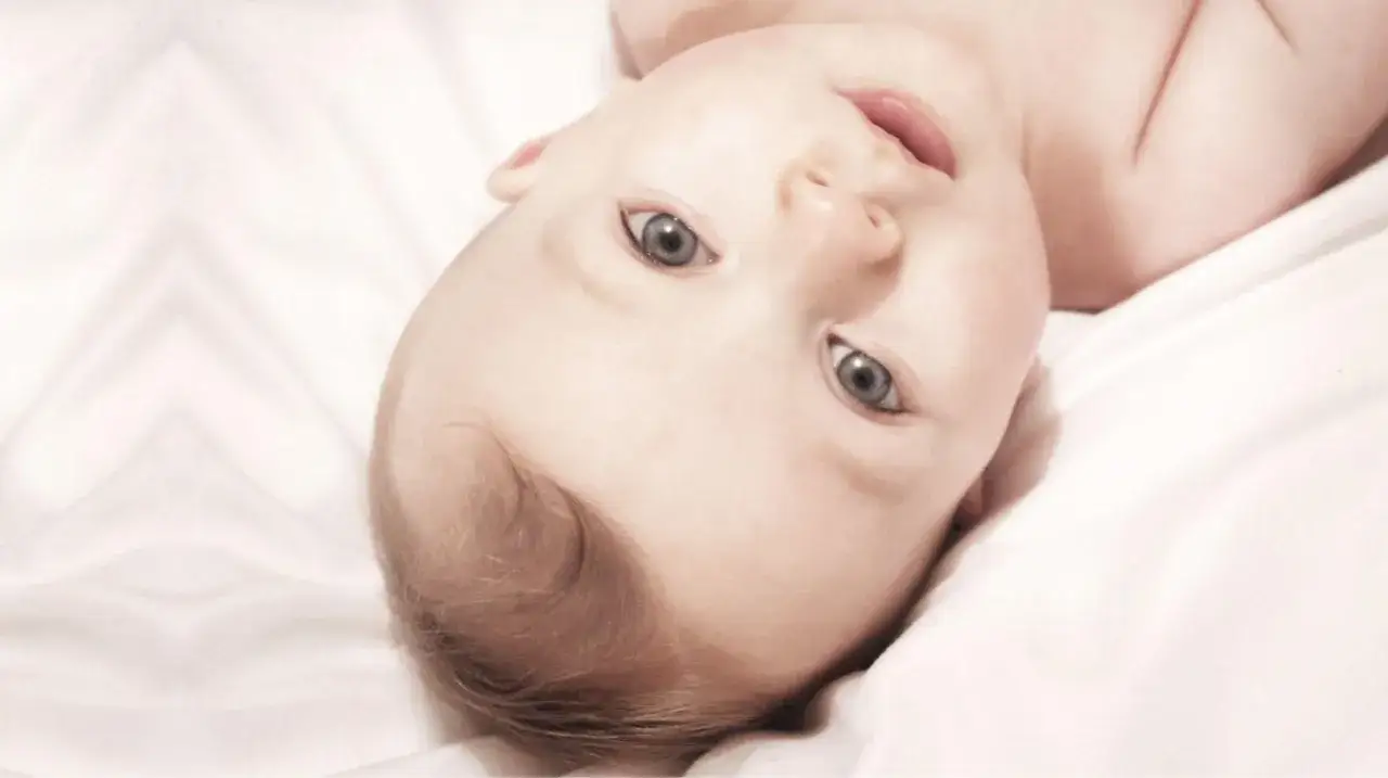 Oczy dziecka, jak objaw zachodzącego słońca, patrzą z jasnej pościeli.