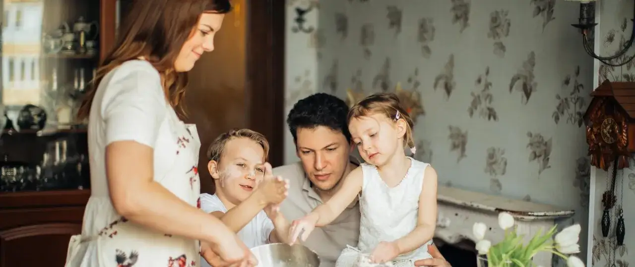 Rodzina piecze ciasto. Mama, tata i dwójka dzieci ubrudzonych mąką. Marzenia o 12 tys na dziecko stają się rzeczywistością.