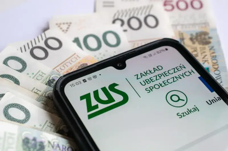 Zasiłek macierzyński 80 czy 100% i 60%? Telefon z aplikacją ZUS na tle polskich banknotów.